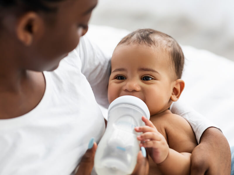 African American Woman Feeding Her Child From Baby Bottle