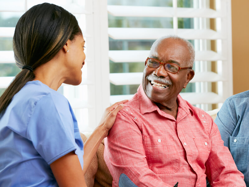 Nurse Making Notes During Home Visit With Senior Couple