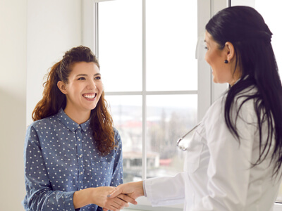 Cheerful Beautiful Young Woman And Her Happy Doctor Meet And Exchange Handshakes